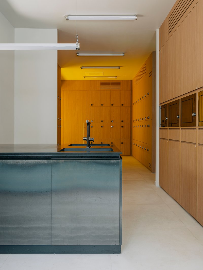 Kitchen with blue metal island beneath yellow locker room framed by timber millwork and white ceiling