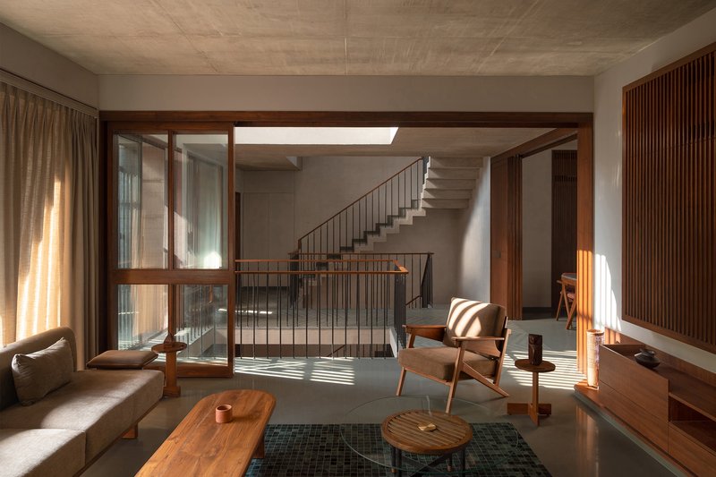 Double-height living room with cantilevered concrete staircase bathed in afternoon sunlight