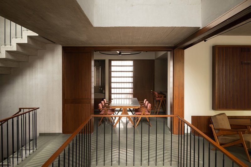 View across stair landing toward timber-framed dining area with horizontal slatted screens