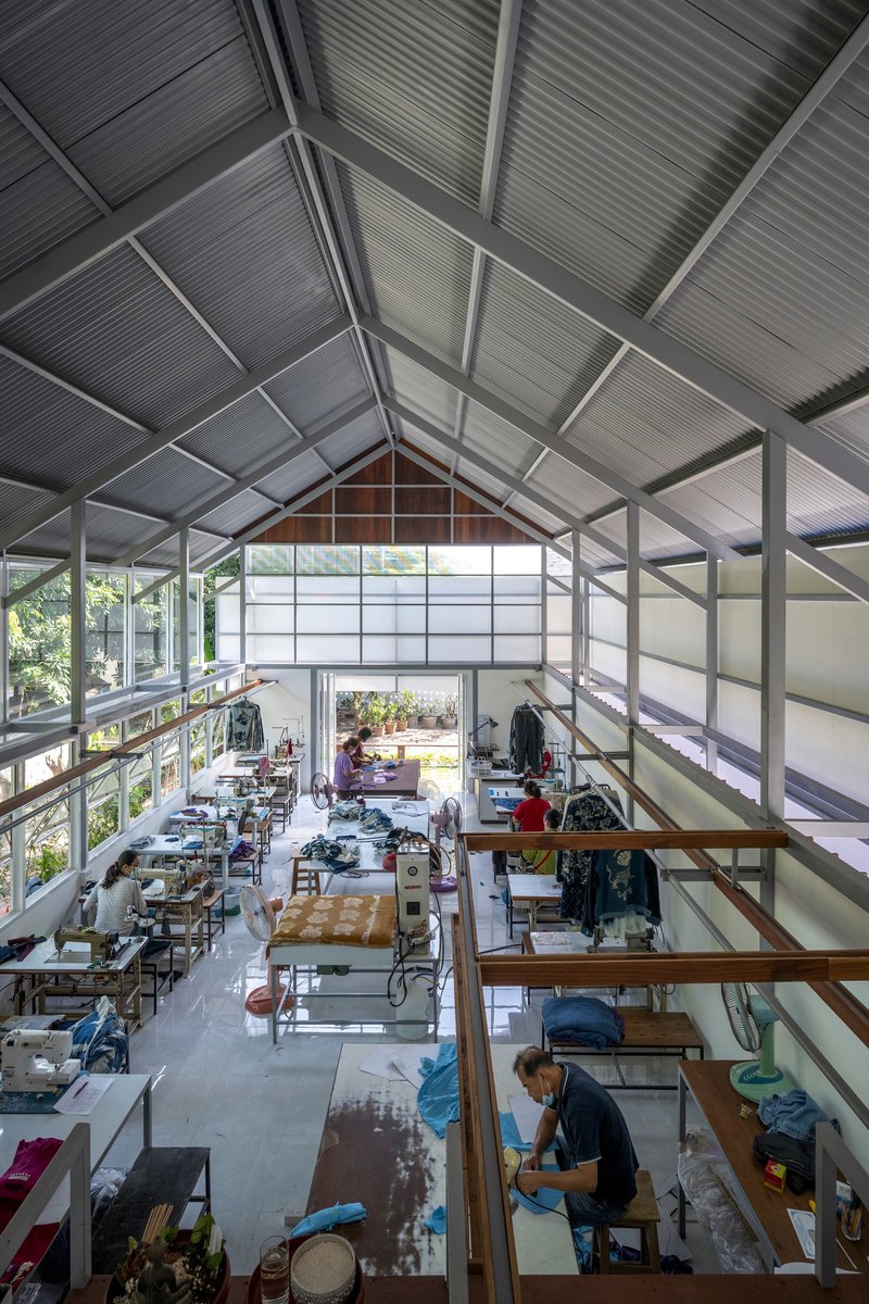 Interior view of the double-height workspace with exposed gabled roof trusses and translucent panels