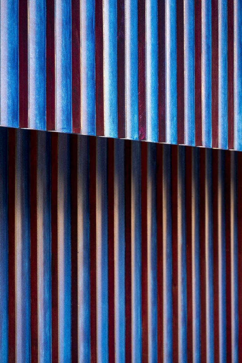 Blue-tinted vertical timber slats with a horizontal shadow line dividing the facade