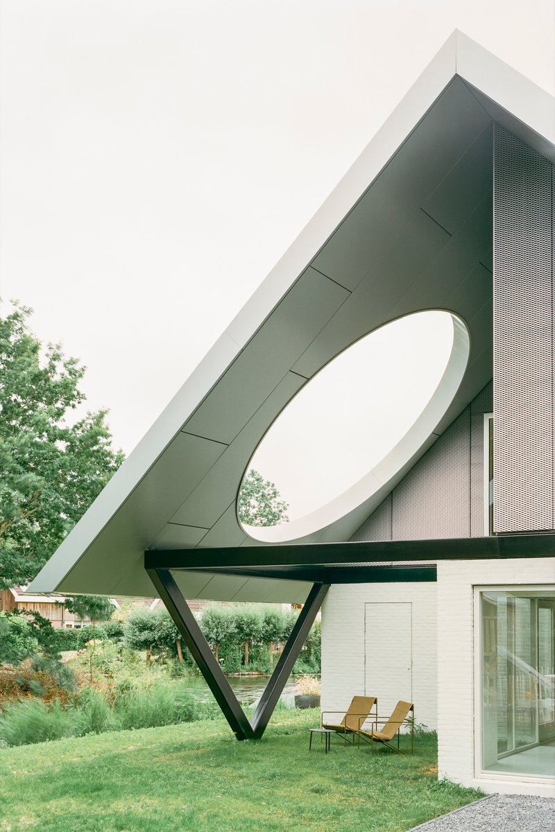 Perforated metal roof canopy with circular aperture and angled steel support over terrace