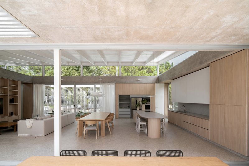 Open-plan kitchen and dining area beneath a white beam structure and timber-lined ceiling