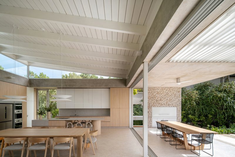 Open-plan kitchen and dining area with white timber ceiling and full-height glazing to the garden