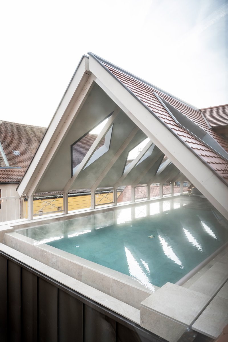 Rooftop pool with concrete edge under a white-painted timber gable and tiled roof