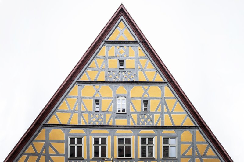Centered view of the triangular timber-framed gable with yellow infill panels against an overcast sky