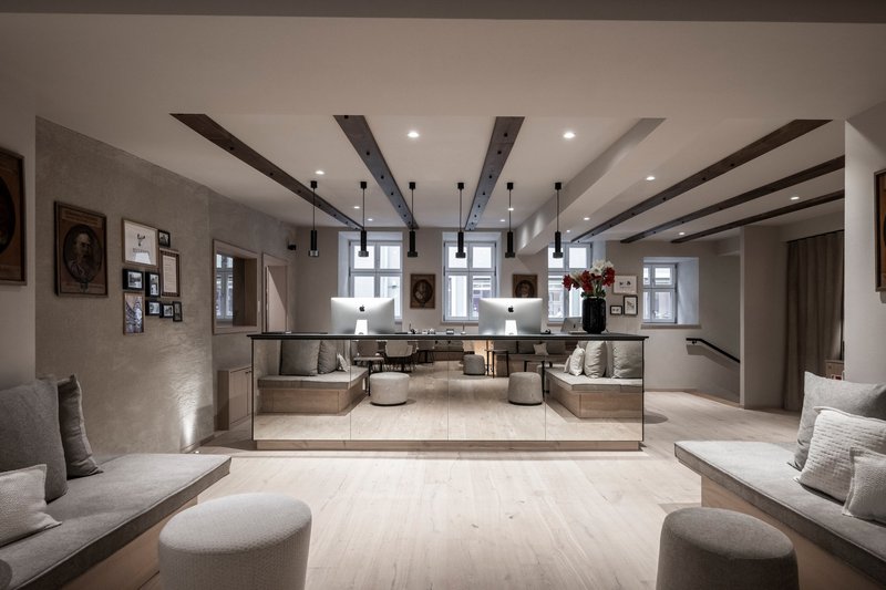 Reception lobby with mirrored front desk and symmetrical seating under exposed timber ceiling beams