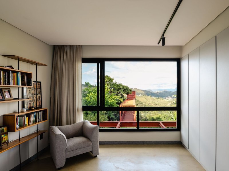 Reading nook with floor-to-ceiling window overlooking the exterior steel pergola and distant valley landscape