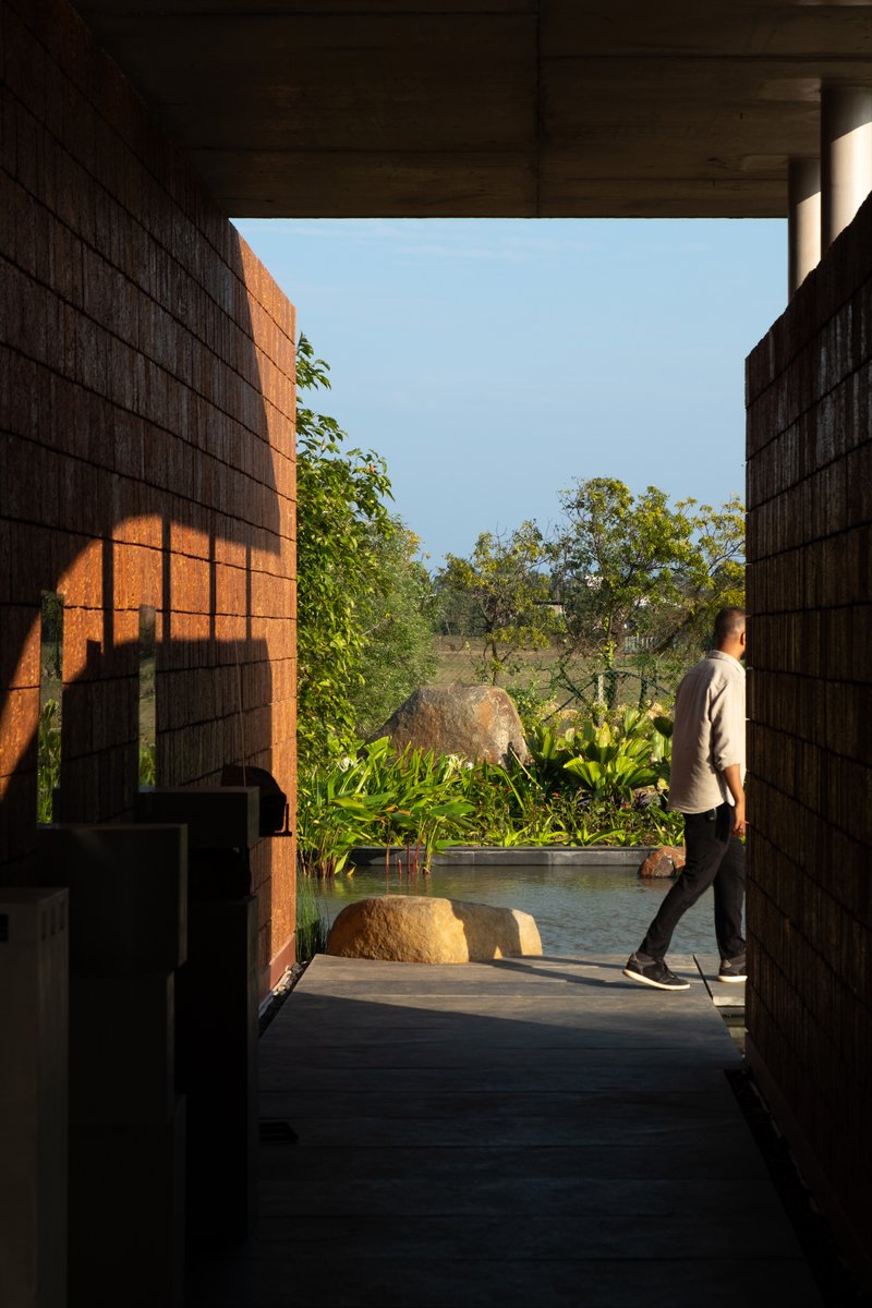 Framed view through covered passage toward courtyard garden with boulders and reflecting pool at dusk