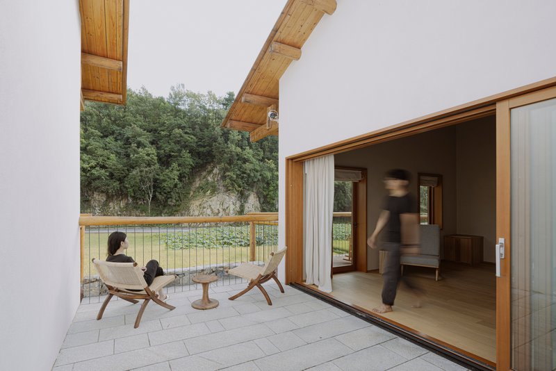 Covered terrace opening to interior living space with figures seated outside and moving through the doorway