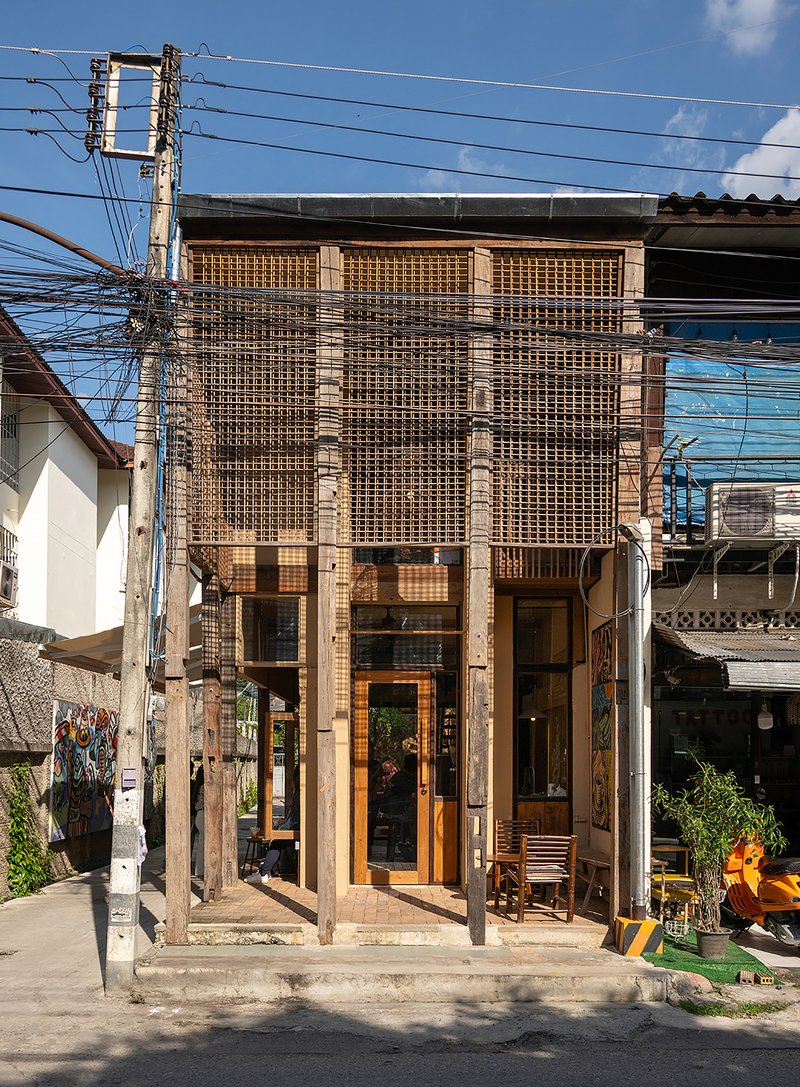 Two-story timber screen facade with brick columns on a residential street beneath overhead power lines