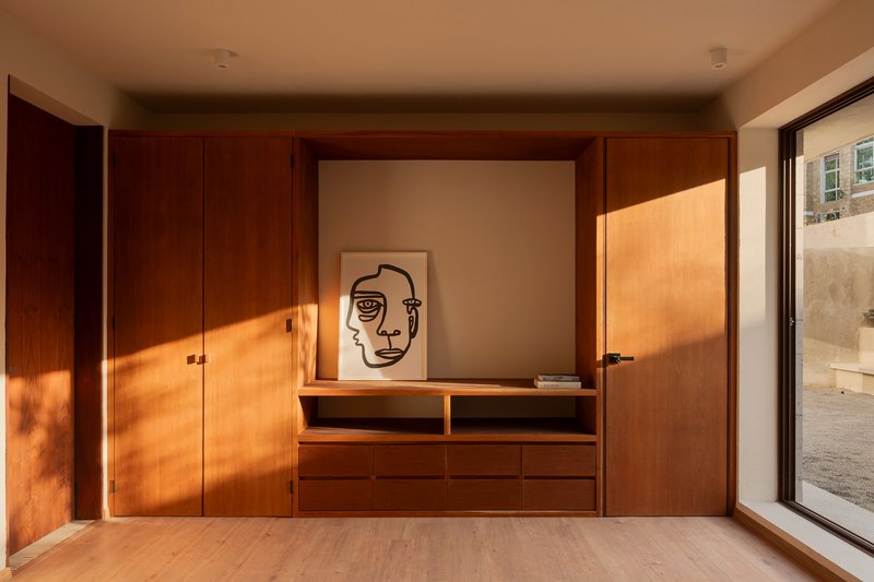Built-in timber credenza and wardrobe wall with warm afternoon light from a courtyard window