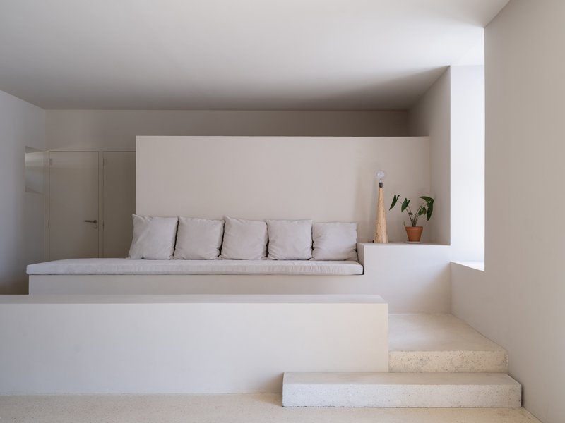 Built-in seating nook with white cushions and stone steps ascending under a low ceiling
