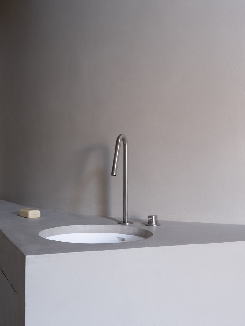 Close-up of integrated sink with high-arc tap and push button drain in pale grey countertop