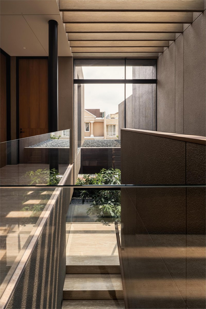 Upper-level hallway with timber ceiling slats and glazing opening to a planted lightwell below