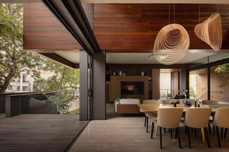 Dining area with folded pendant lights opening to a timber deck through sliding glass doors