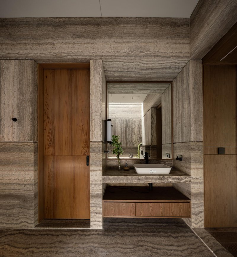 Vanity counter in banded travertine with timber door and recessed ceiling beam detail
