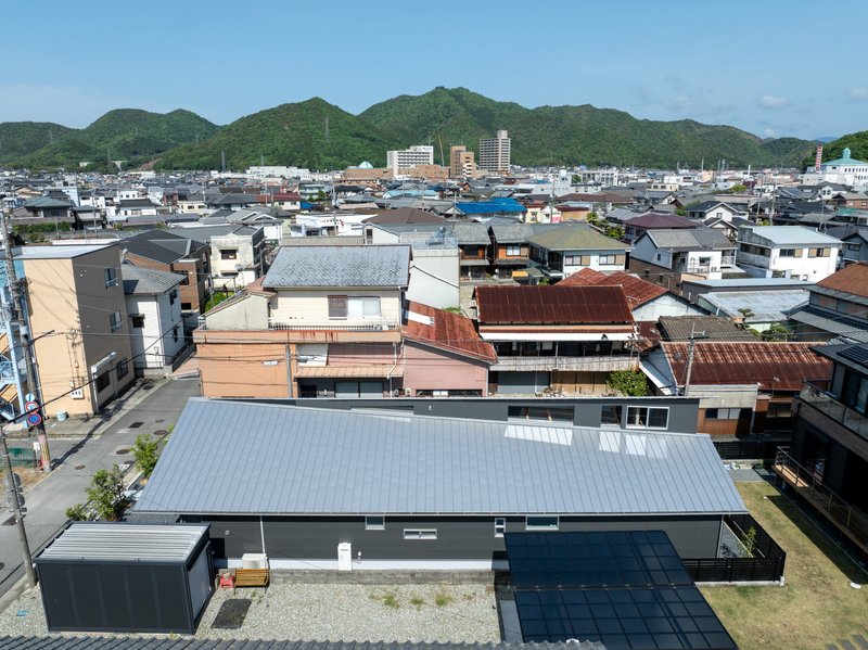 Elevated view showing the low-slung metal roof and dark courtyard wall within the dense residential fabric