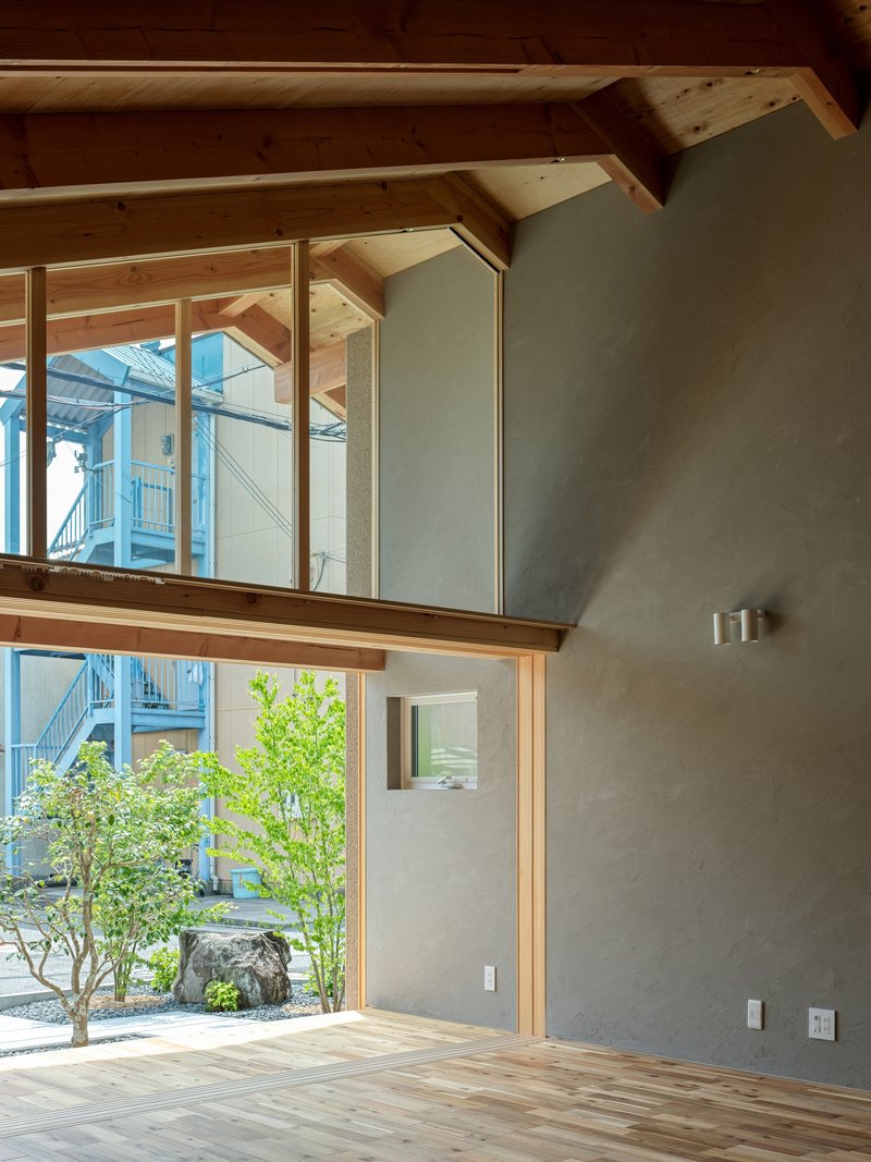 Double-height interior with timber frame structure and floor-to-ceiling glazing overlooking a courtyard garden