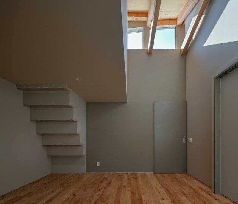Second-floor room with floating white shelves, clerestory windows, and timber flooring at the ceiling edge