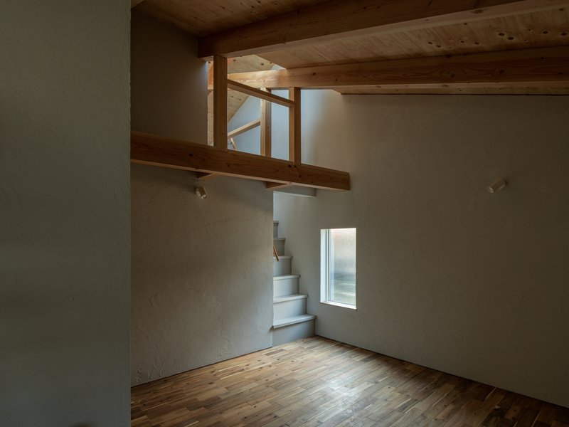 Folded metal staircase ascending toward timber loft with exposed beams and natural light from above