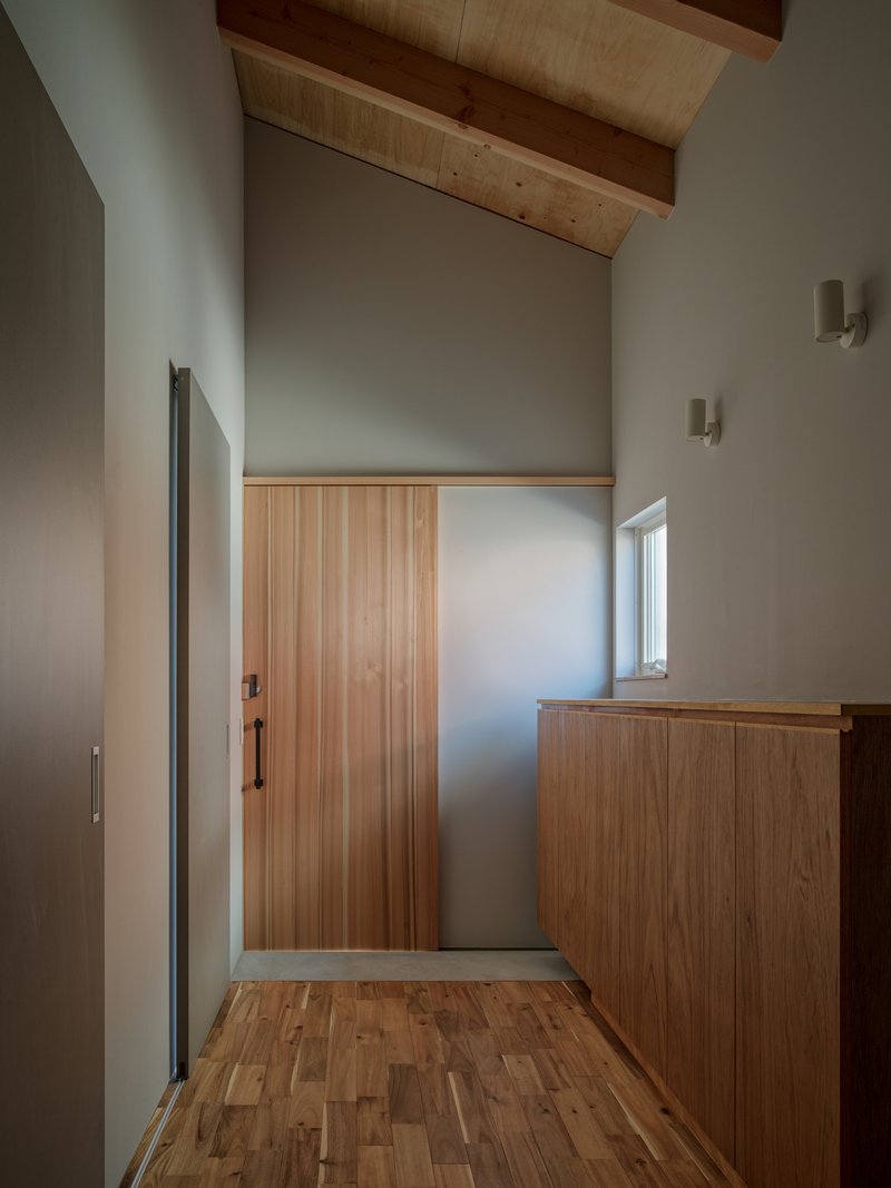 Entry hall with timber door and built-in cabinet under vaulted ceiling with exposed wood rafters