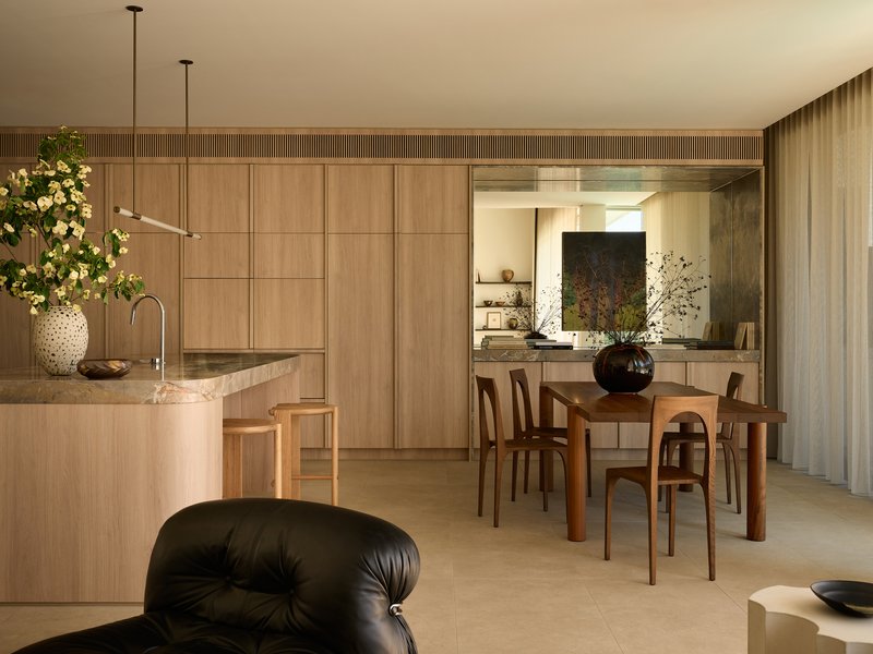 Open-plan kitchen and dining area with oak veneer cabinetry, stone benchtop and fluted timber ceiling detail