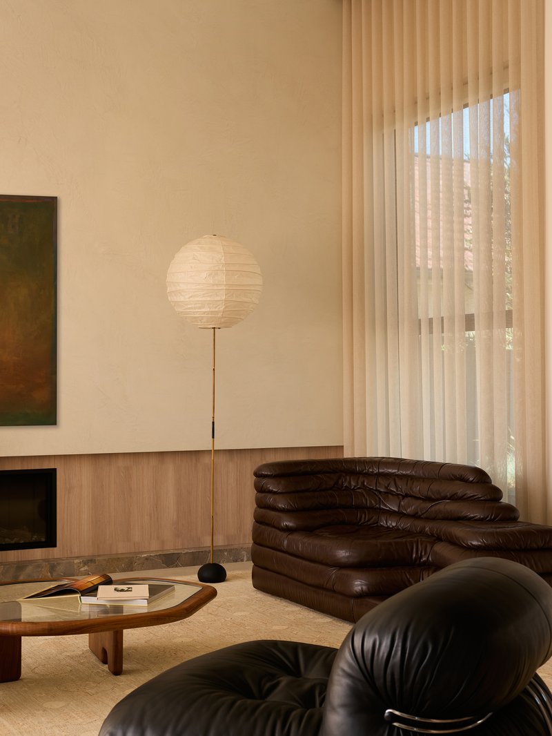 Living room with paper floor lamp, vertical blinds, and brown leather seating in warm afternoon light