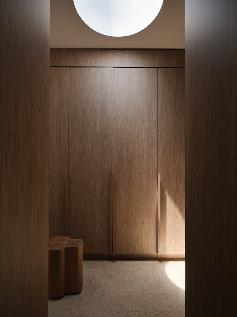 Timber-paneled entryway with recessed ceiling skylight and afternoon sunlight falling across the floor