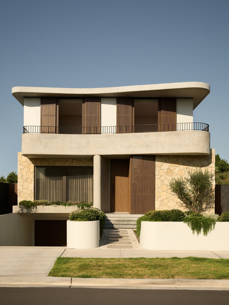 Front elevation showing timber shutters opened on the upper level balcony under clear blue sky