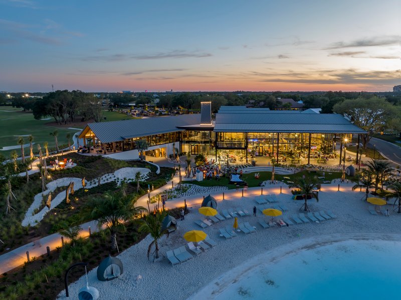 Aerial view of the poolside complex with sandy beach area and umbrella loungers at sunset