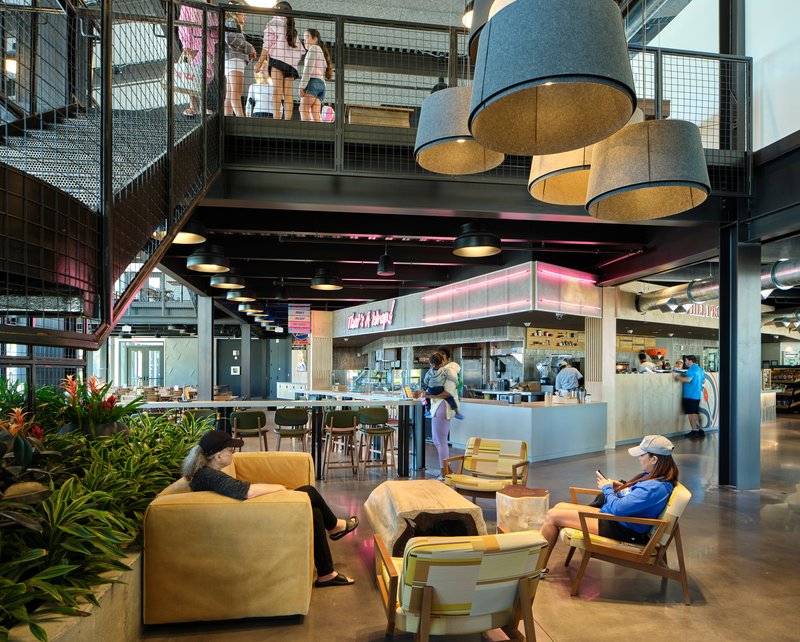Double-height interior with mezzanine, wire mesh railings, pendant lighting and seating area below upper walkway