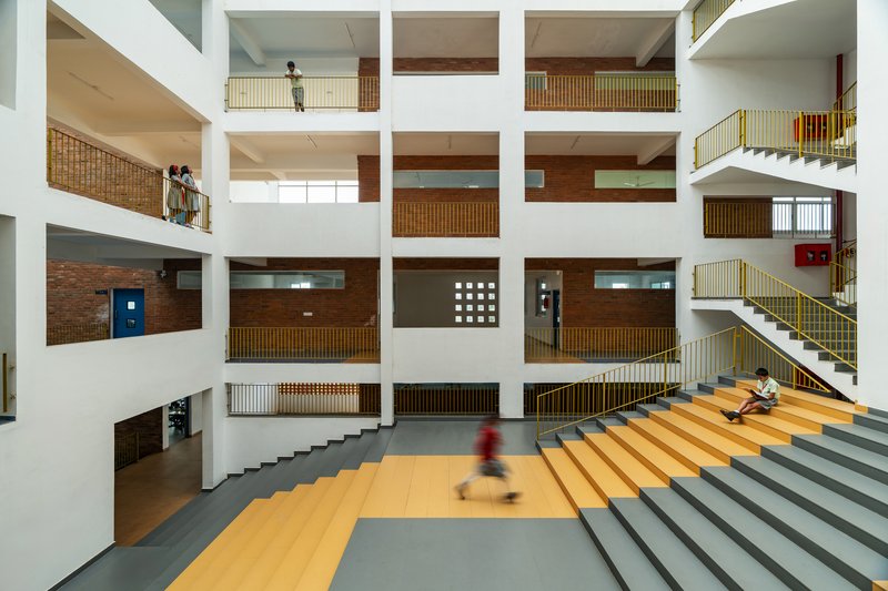 Interior atrium with stacked openings, yellow and gray tiered steps and a child in motion