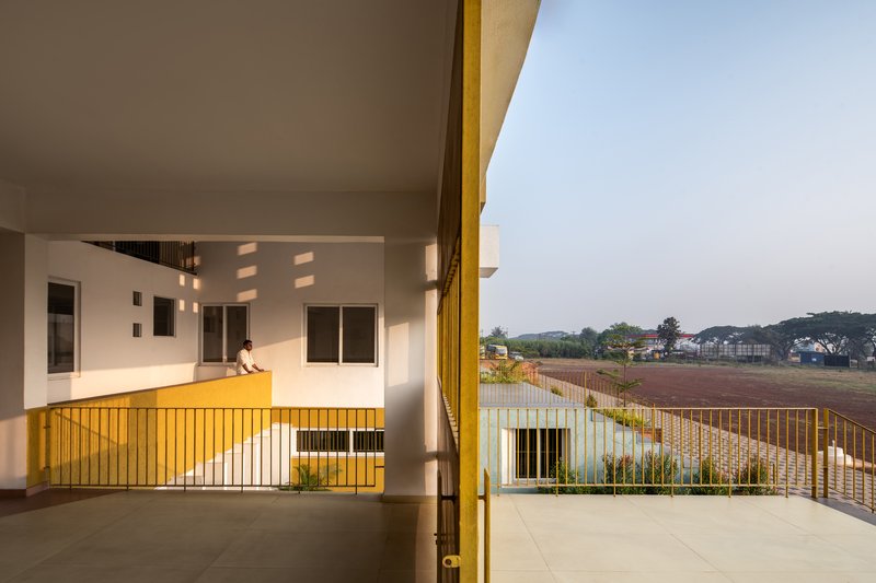 Covered terrace with yellow metal railing overlooking the open field at dusk
