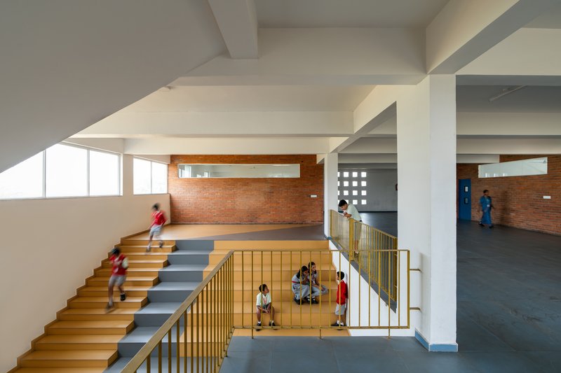 Multi-level atrium view showing the split stair and brass-colored railings under coffered concrete ceilings