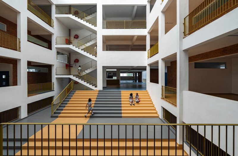 Central atrium with multi-story white balconies and striped stair where children play on the steps