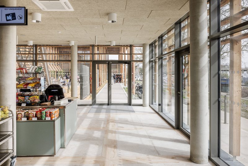 Entrance lobby with cylindrical concrete columns and floor-to-ceiling glazing framed by timber brise-soleil