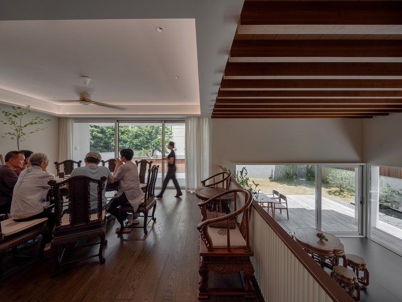Double-height dining area with exposed timber beams and sliding glass walls opening to a terrace