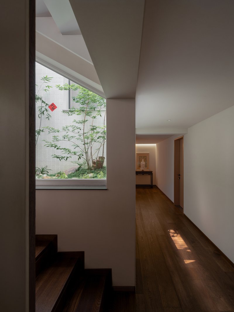 Upper floor hallway with timber flooring and window framing a small courtyard garden with bamboo