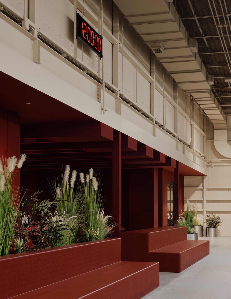 Storefront opening framed by rust-colored portal with tiered planters filled with tall grasses and succulents