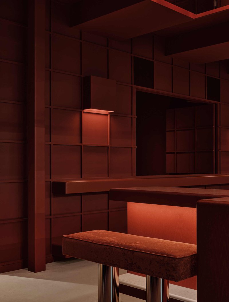 Corner detail of gridded terracotta shelving system with integrated bench and warm accent lighting