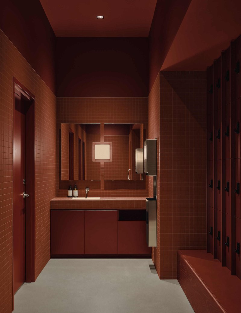 Locker room vanity area with terracotta tile walls, floating sink counter and warm ambient lighting