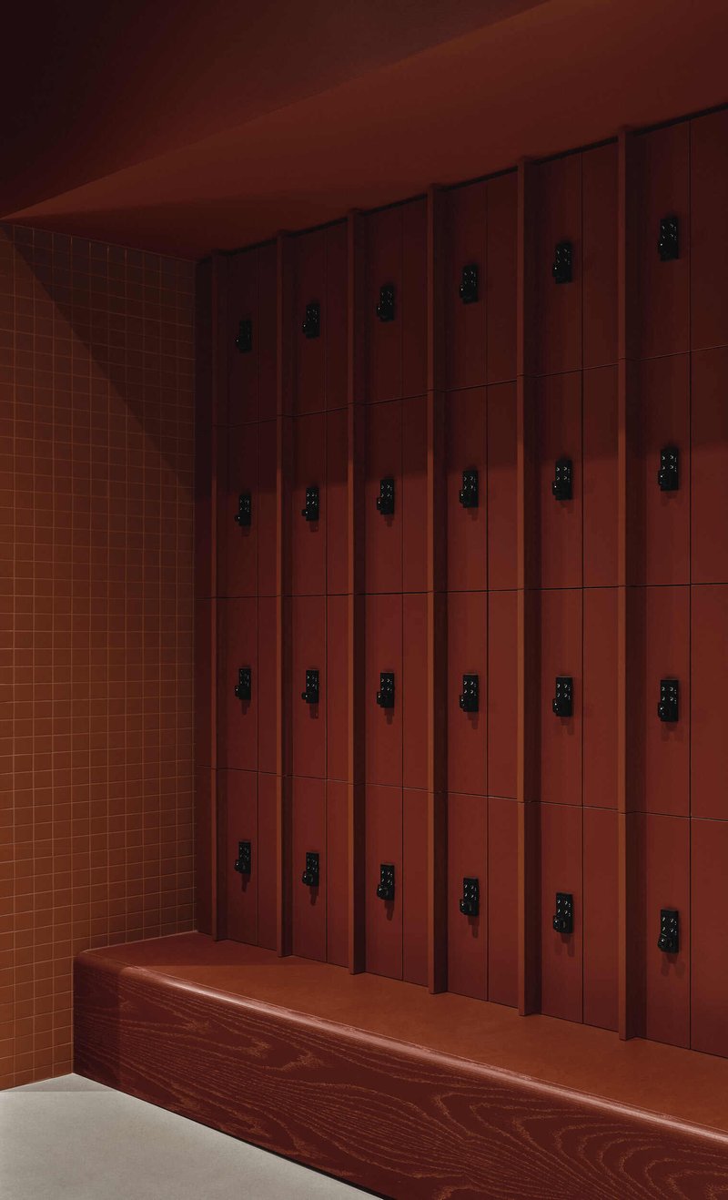 Wood locker wall with black metal latches above a bench beside a tile wall