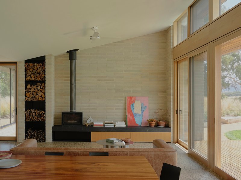 Living space with black wood stove and stacked firewood niche against a masonry block wall