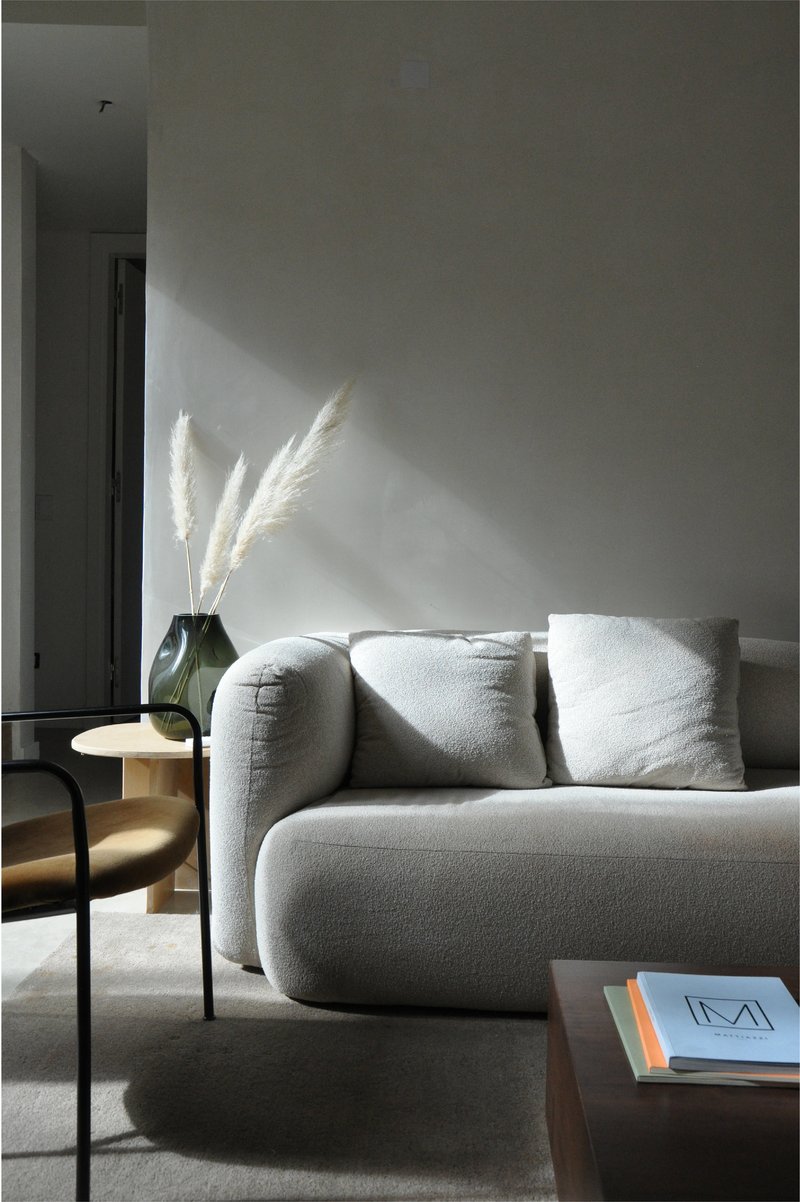 Grey upholstered sofa with pampas grass in morning sunlight streaming across the wall