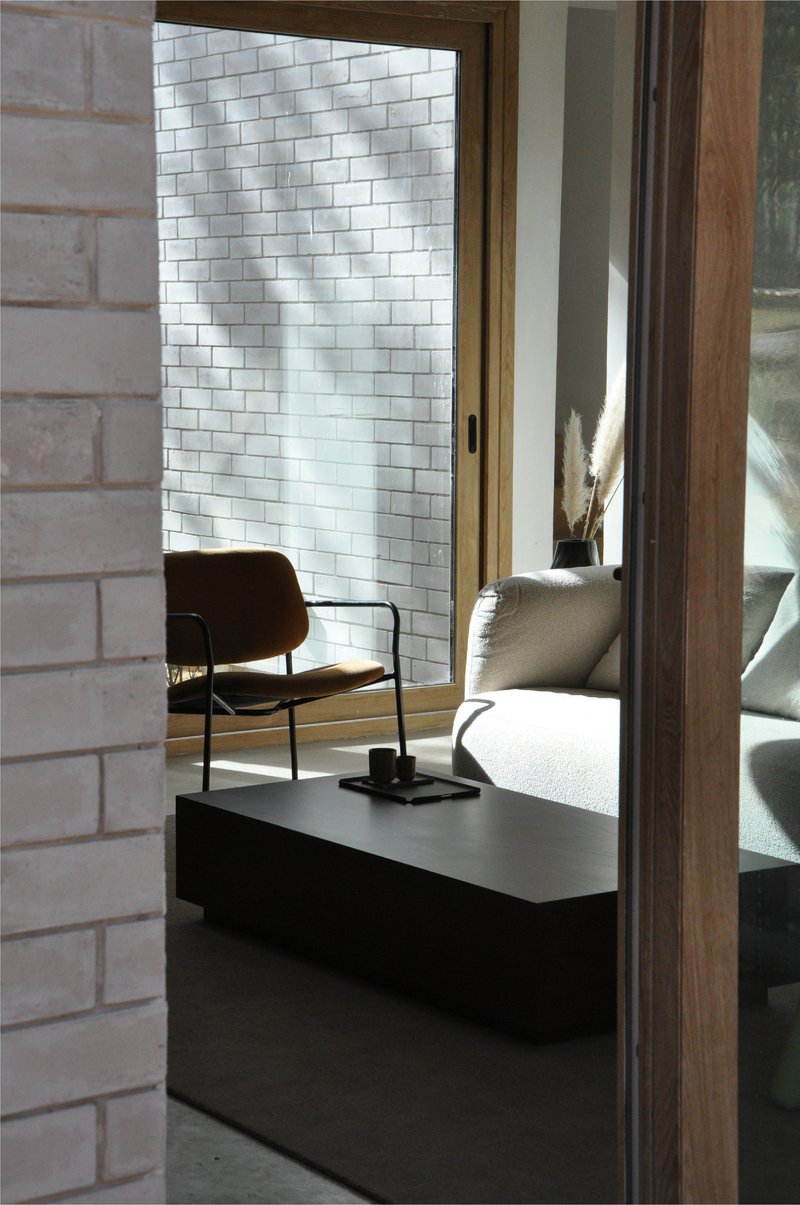 View through timber doorframe to white brick wall with sunlight on polished concrete floor