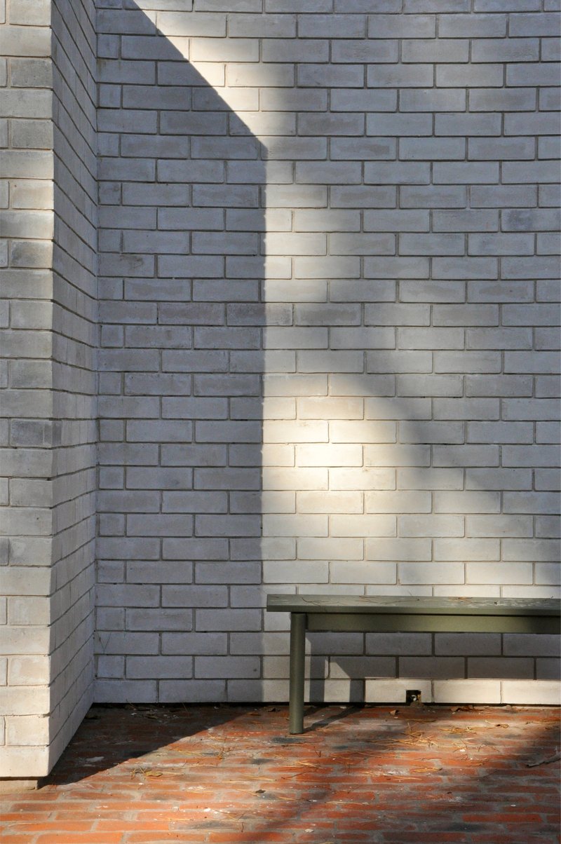 Interior corner with white brick walls and orange tile floor in dappled sunlight