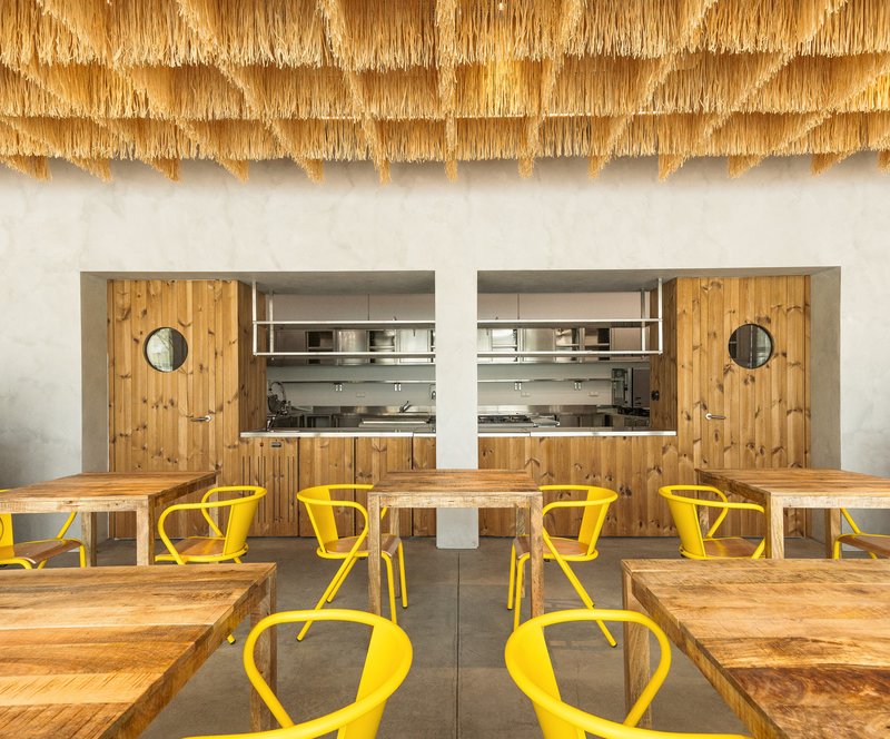Symmetrical timber kitchen alcoves with circular portholes beneath fringed raffia ceiling edge