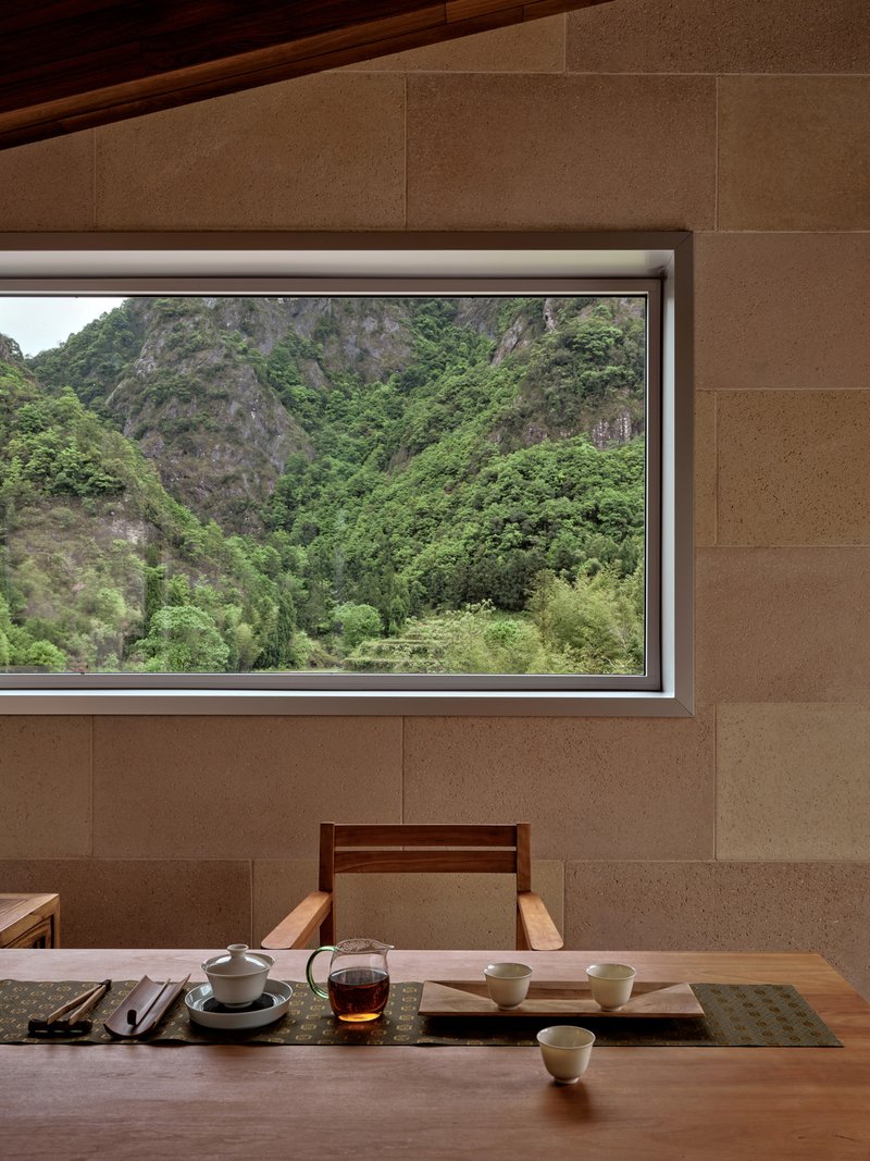 Dining table with tea set beneath horizontal window framing view of forested karst mountains