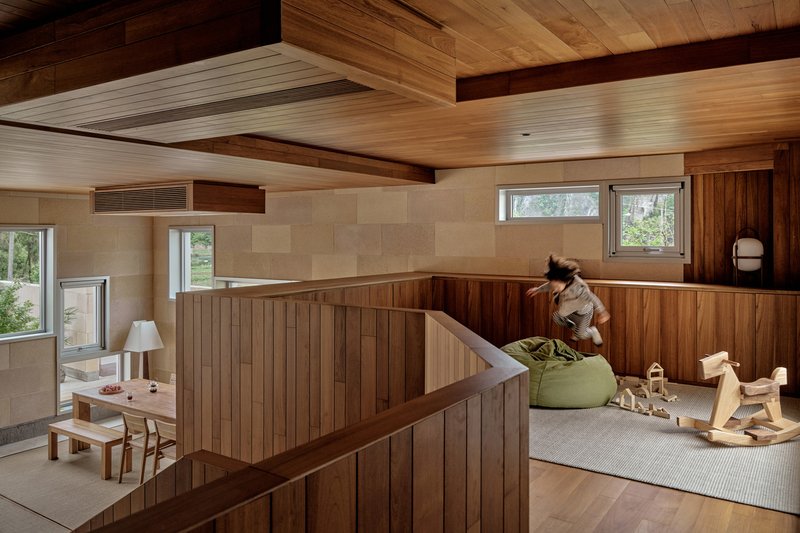 Upper level play area with vertical wood paneling and stairwell railing in afternoon sun